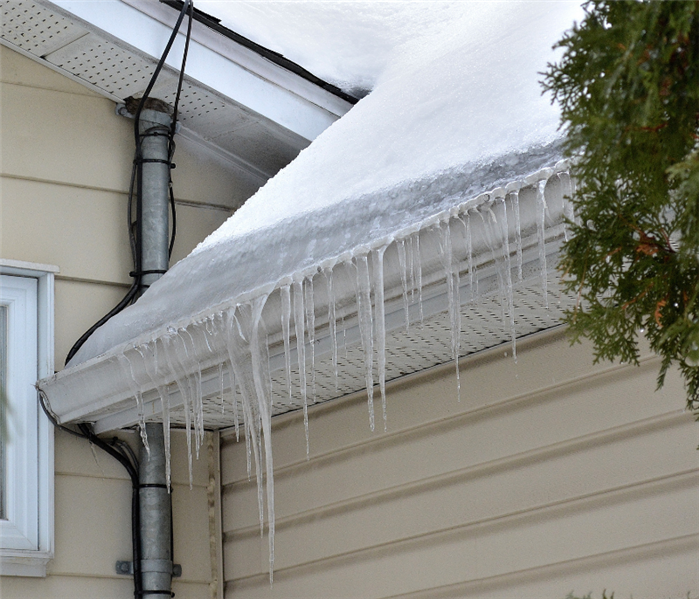 ice dam forming on edge of roof covered with snow